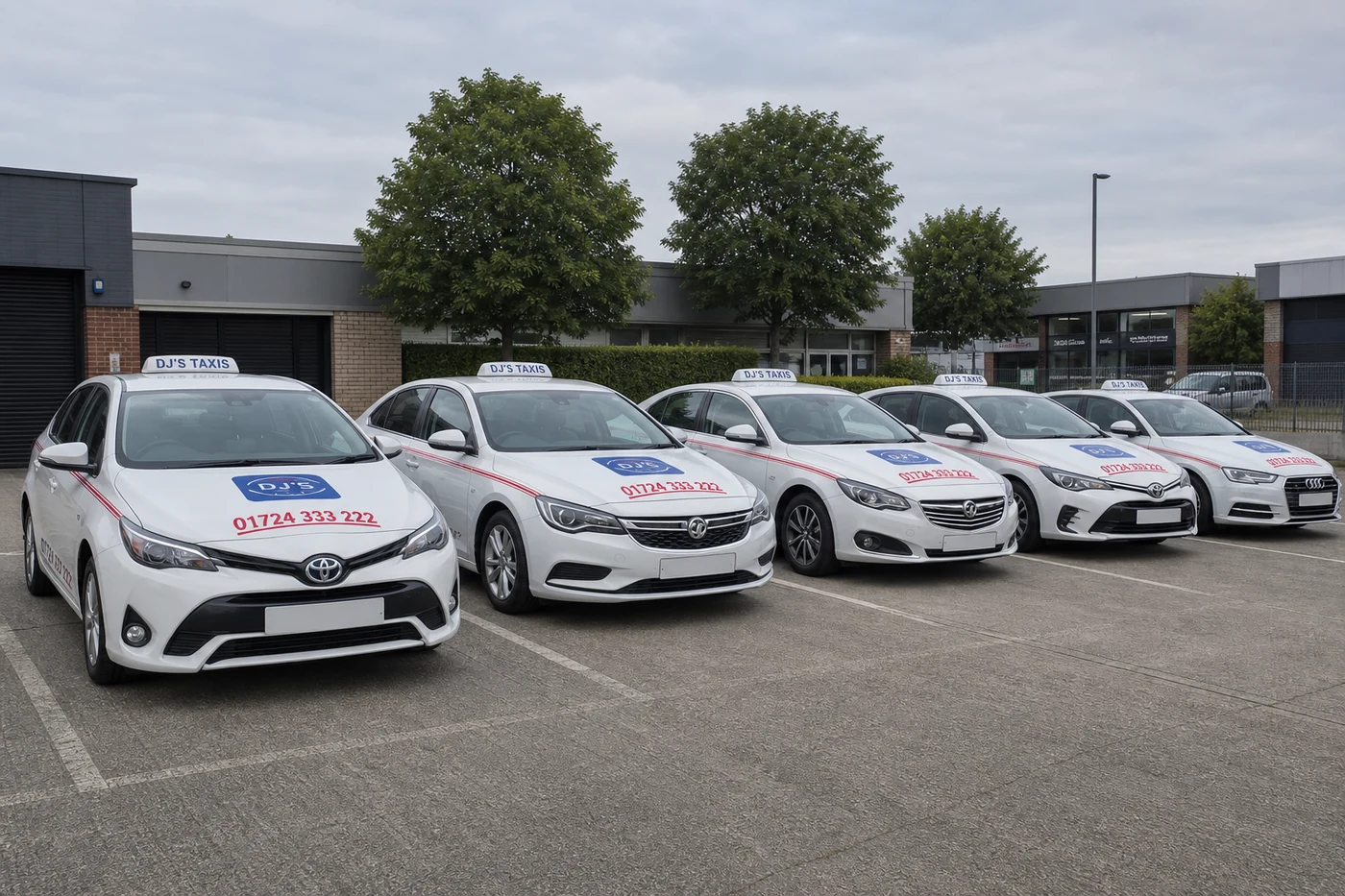 Lineup of silver and white branded DJ's Taxis vehicles parked in their Scunthorpe commercial dispatch yard
